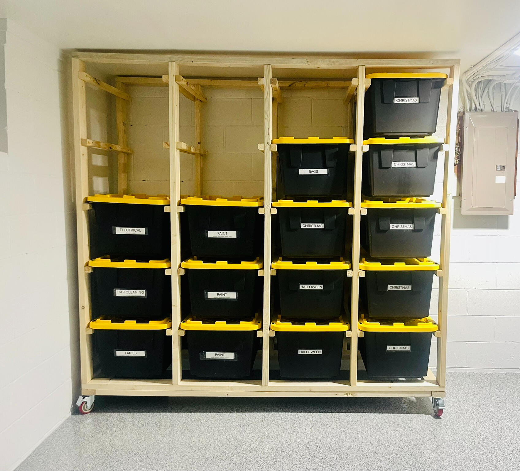 3 wide x 4 high system A cleanly organized garage featuring one wooden bin storage unit that is holding 9 black and yellow storage bins. The unit is 3 wide x 3 high and sits on top of casters.