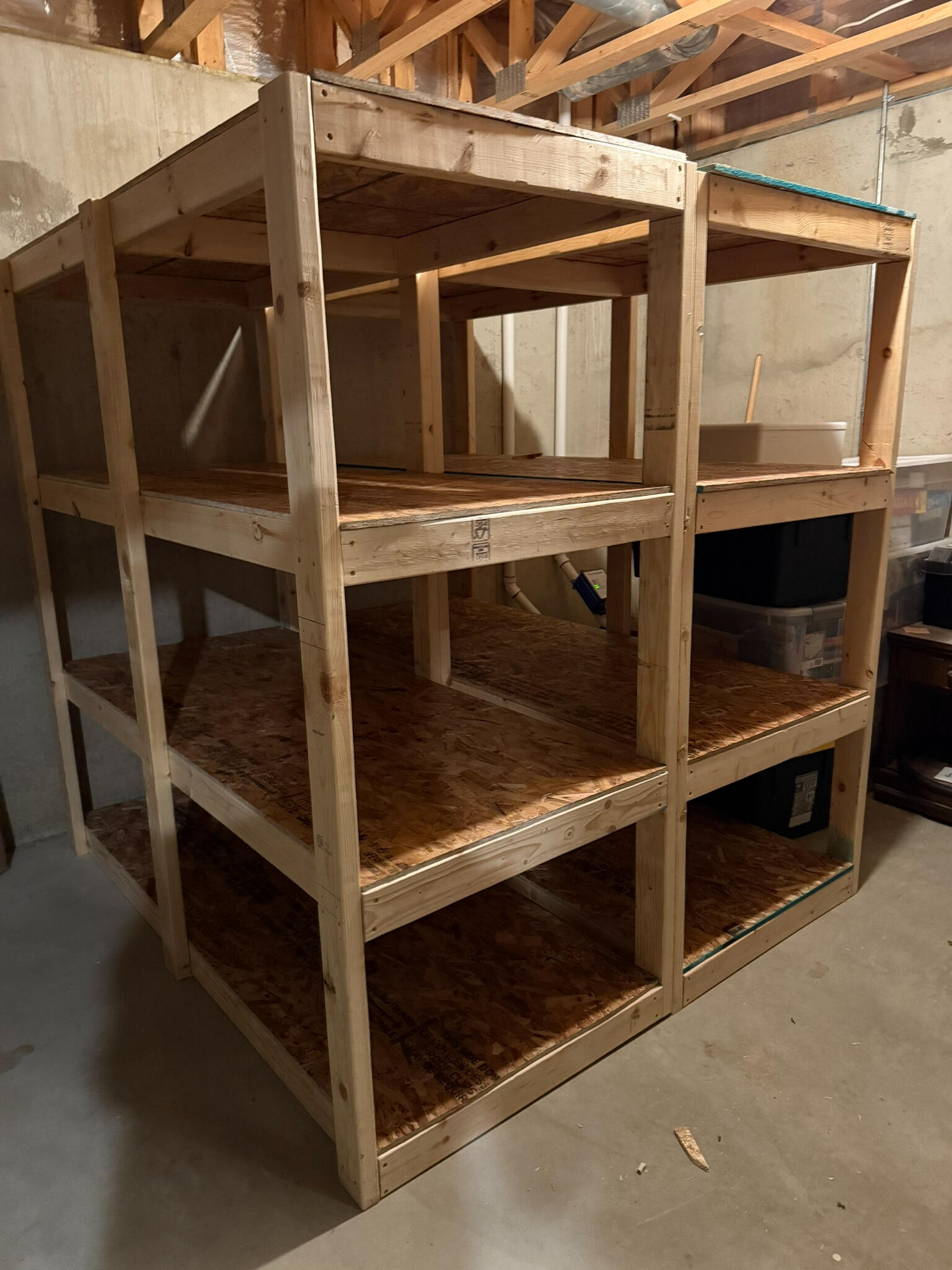 A wooden storage shelving unit is pictured. The unit has 4 rows of shelving, each supported by a flat piece of plywood.