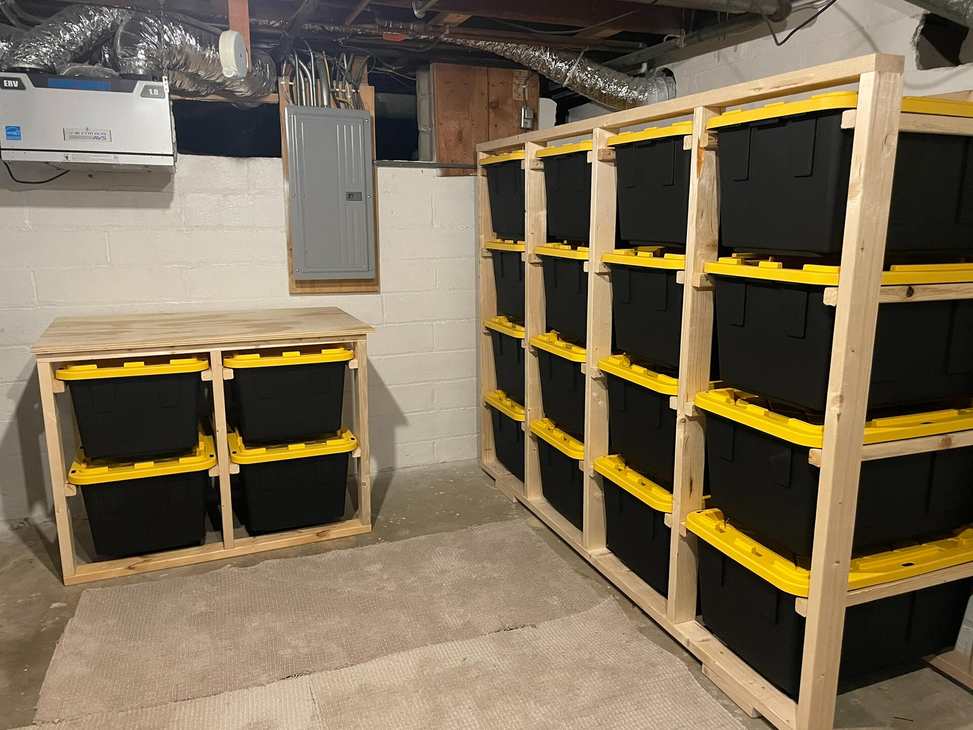 Solid wood storage system that contains 5 columns and support beams on the bottom and top. The unit is holding 16 black and yellow totes that are perfectly symmetrical from horizontal to vertical.